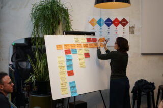 Pauline est en train d'accrocher des PostIts, sur un Paper Board.